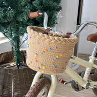 Pleciony koszyk rowerowy ze sznura z pomponami i skórzanymi paskami na kierownicę