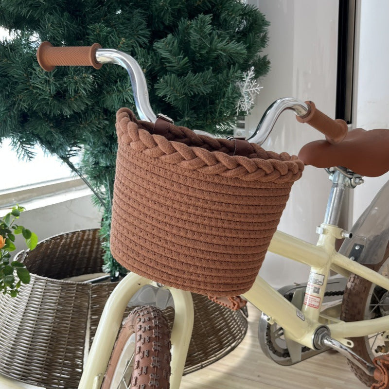 Pleciony koszyk rowerowy ze sznura z pomponami i skórzanymi paskami na kierownicę